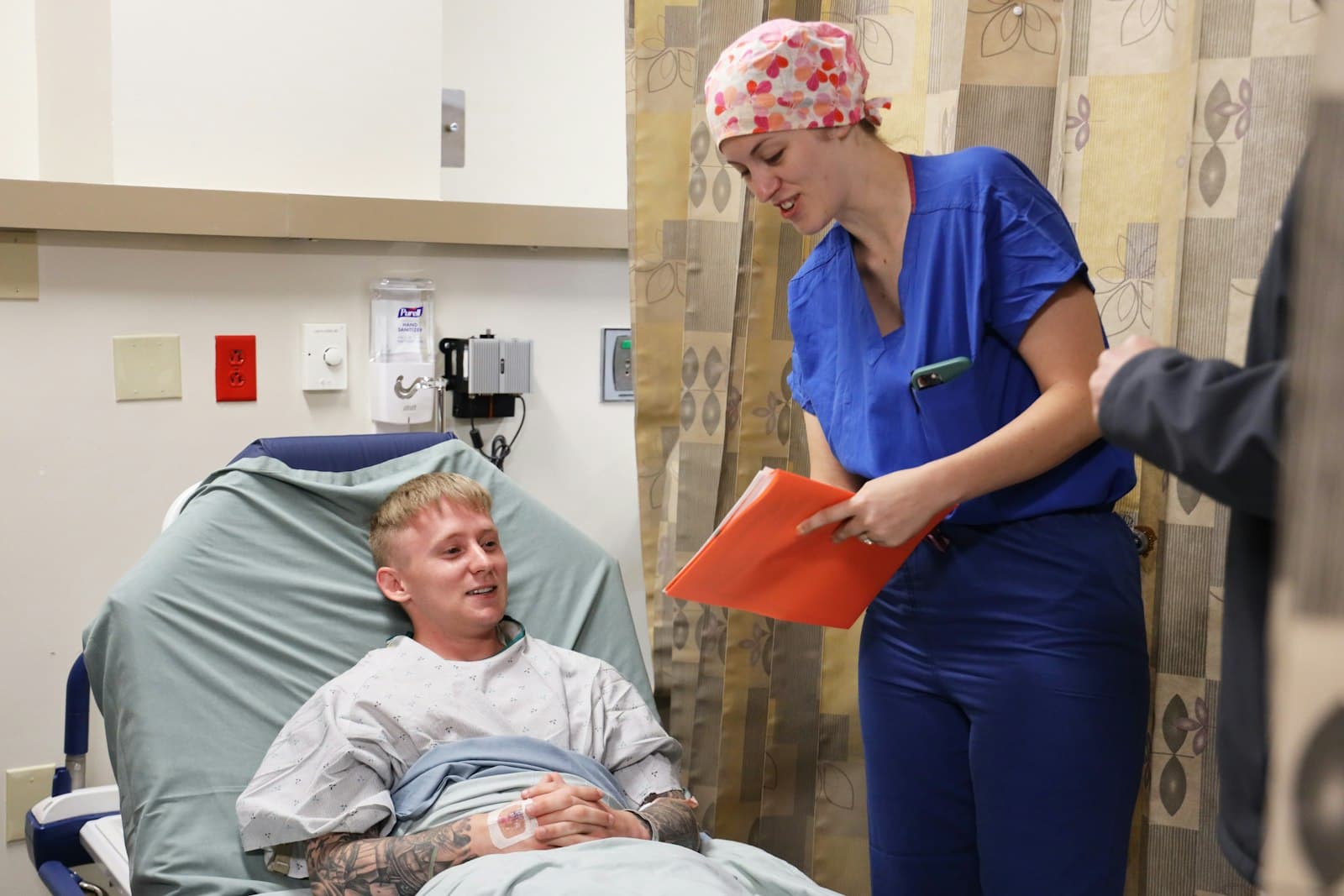 A smiling nurse talking with a patient in a hospital bed