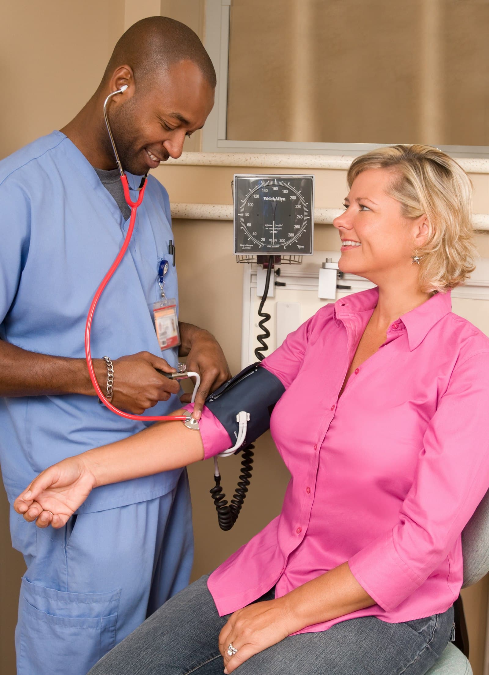A smiling nurse checking a patient's blood pressure